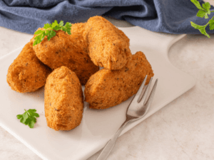 This dish is a combination of codfish, mashed potatoes, onions, eggs, and parsley, all mixed together, shaped into balls, and deep-fried.