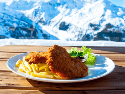 Schnitzel is a tenderized piece of meat like chicken, beef, veal, or pork. It is then covered in egg, flour, and breadcrumbs before frying in oil or butter.