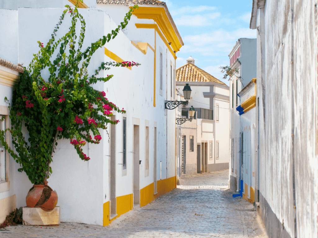 Image of street in Portugal with white buildings and yellow and blue trim on sunny day while traveling gluten free in portugal.