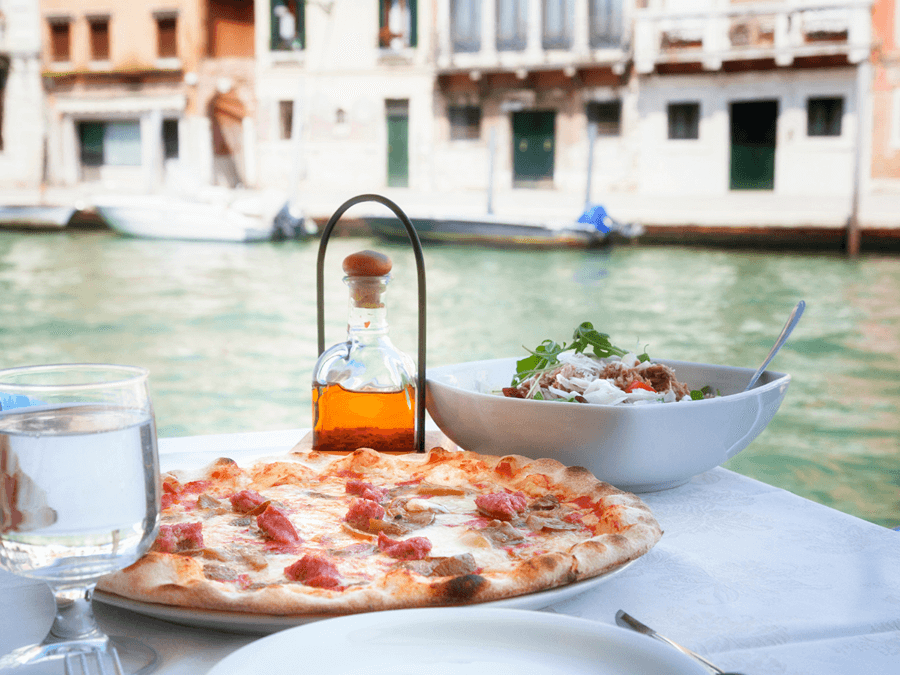 enjoying a pizza for dinner overlooking water while eating dairy free in italy.
