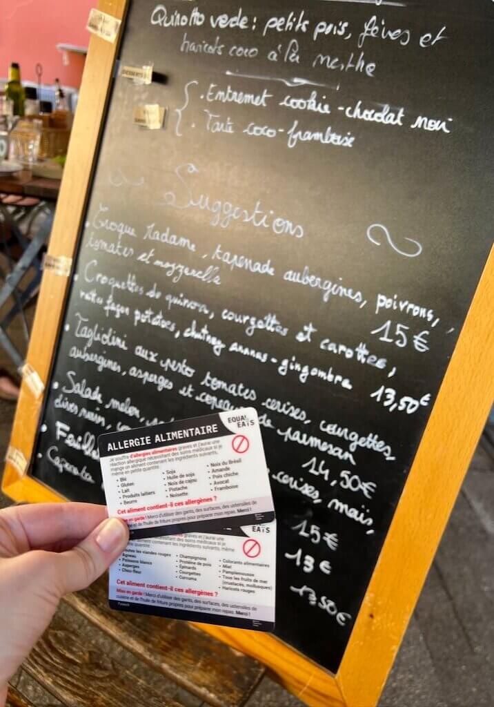 Lauren Scheffer holding Equal Eats Allergy Chef cards in restaurant.